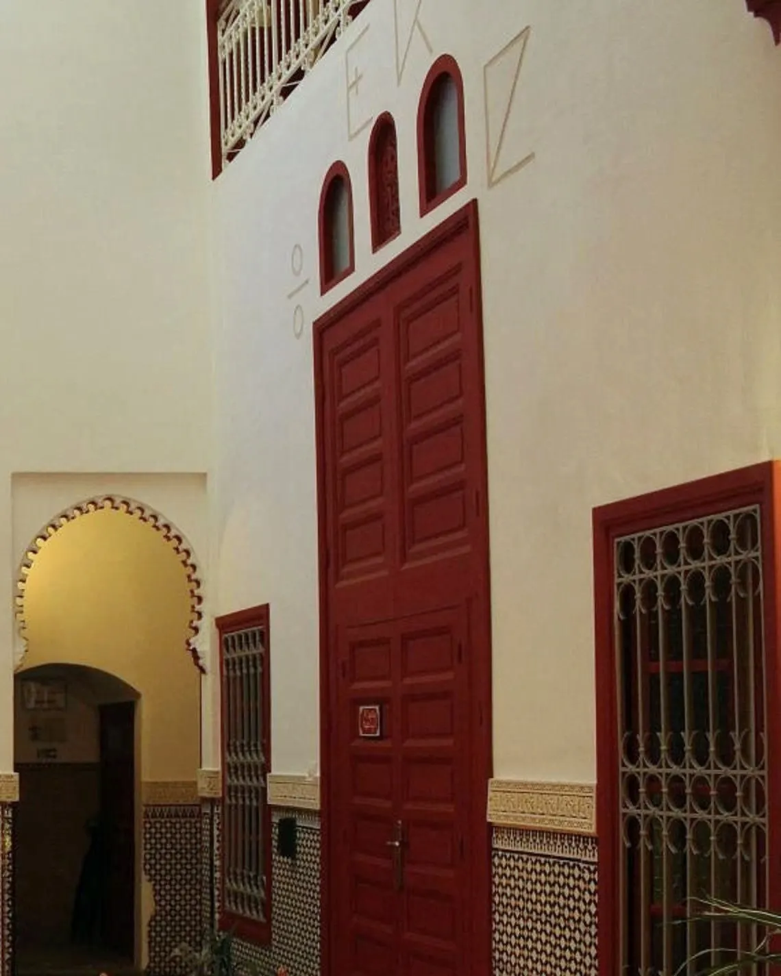 Un arco de herradura y una alta puerta de cedro roja en el patio