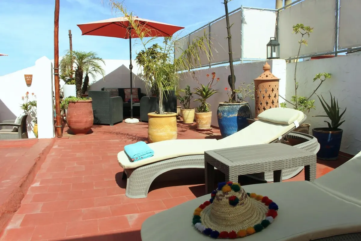 The terrace by day: loungers, red parasol, terracotta floor