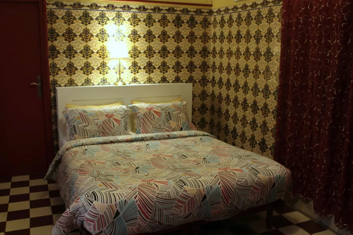 Al Mansour bed with patterned cover among zellige walls