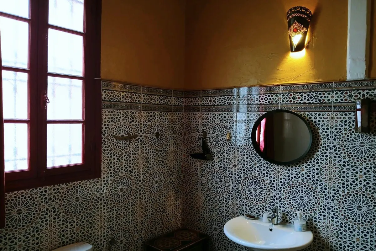 Al Mansour bathroom: zellige, round mirror, pedestal basin