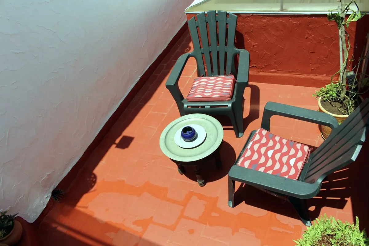 Sur la terrasse, côté Bouregreg : deux fauteuils bleu canard, coussins rouges