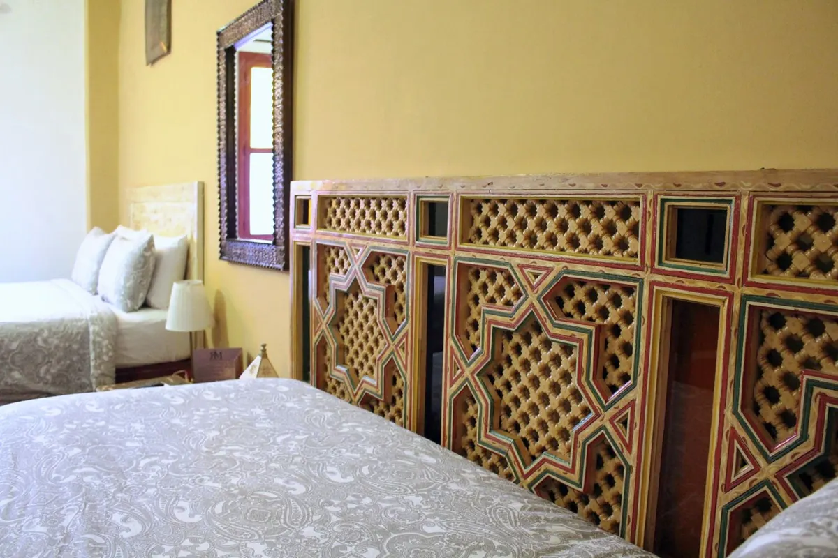 Bed beside a carved wooden moucharabieh screen