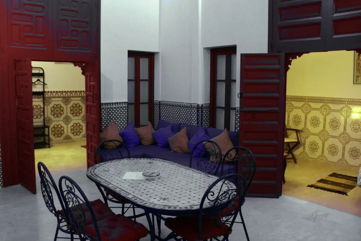 Hassan suite: the private patio-salon with mosaic table and carved red doors