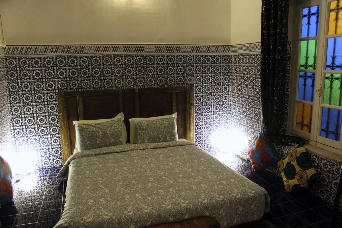 R’Batia room: bed, zellige wall and stained-glass window