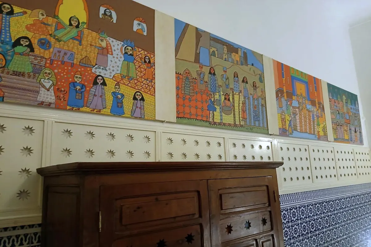 Frieze of naive paintings above a carved chest in R’Batia